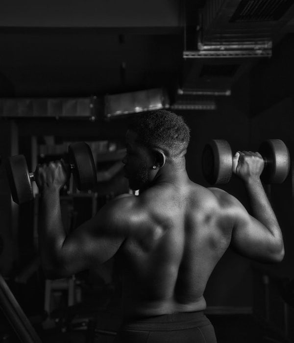 Muscular man performing strength exercises in a modern dark gym environment